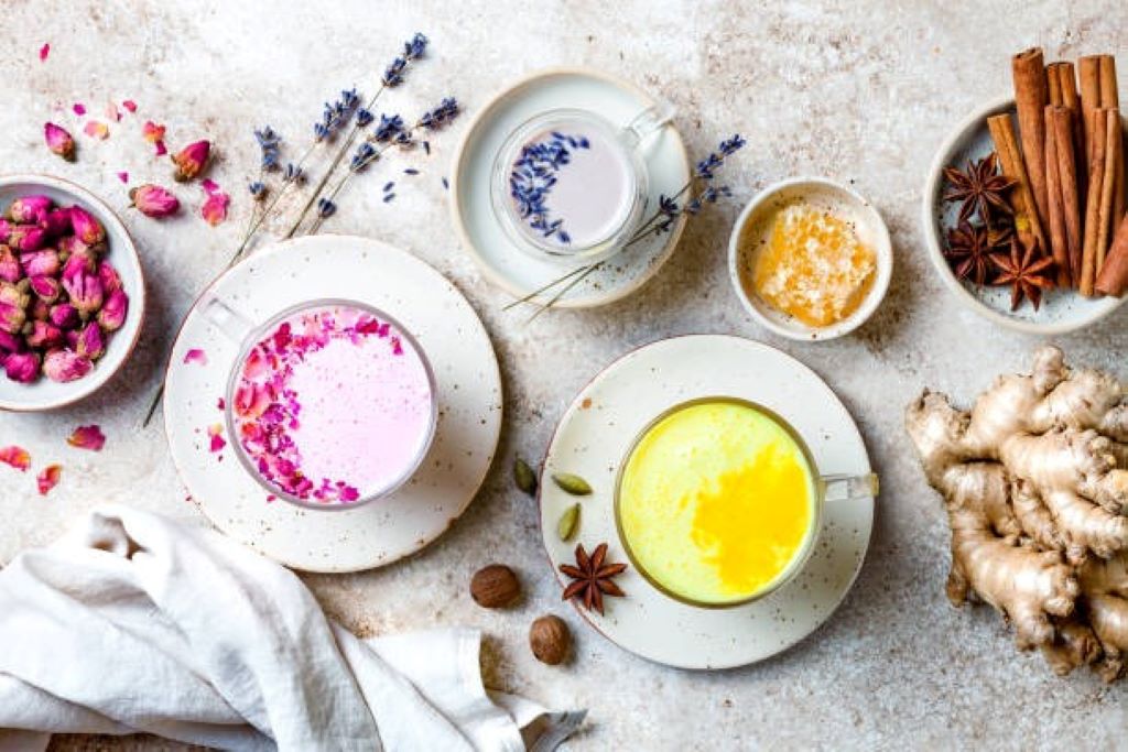 A side-by-side comparison image showing a yellow mug of golden milk on one side and a light purple mug of moon milk on the other