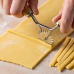 Cutting fresh pasta sheet with fluted edge cutter