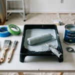 A set of affordable painting tools including brushes, roller, and painter’s tape arranged on a white surface ready for a DIY home project
