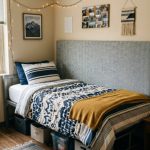 A neatly wrapped fabric pillow headboard leaning against a dorm room wall behind a twin bed