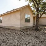 Cracked concrete foundation beside a residential home